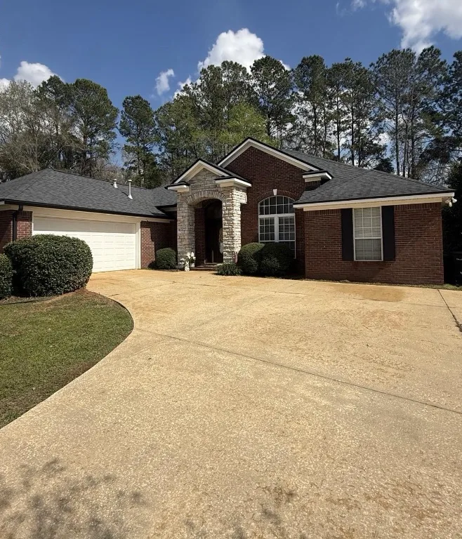 After: residential driveway cleaning in front of a brick home